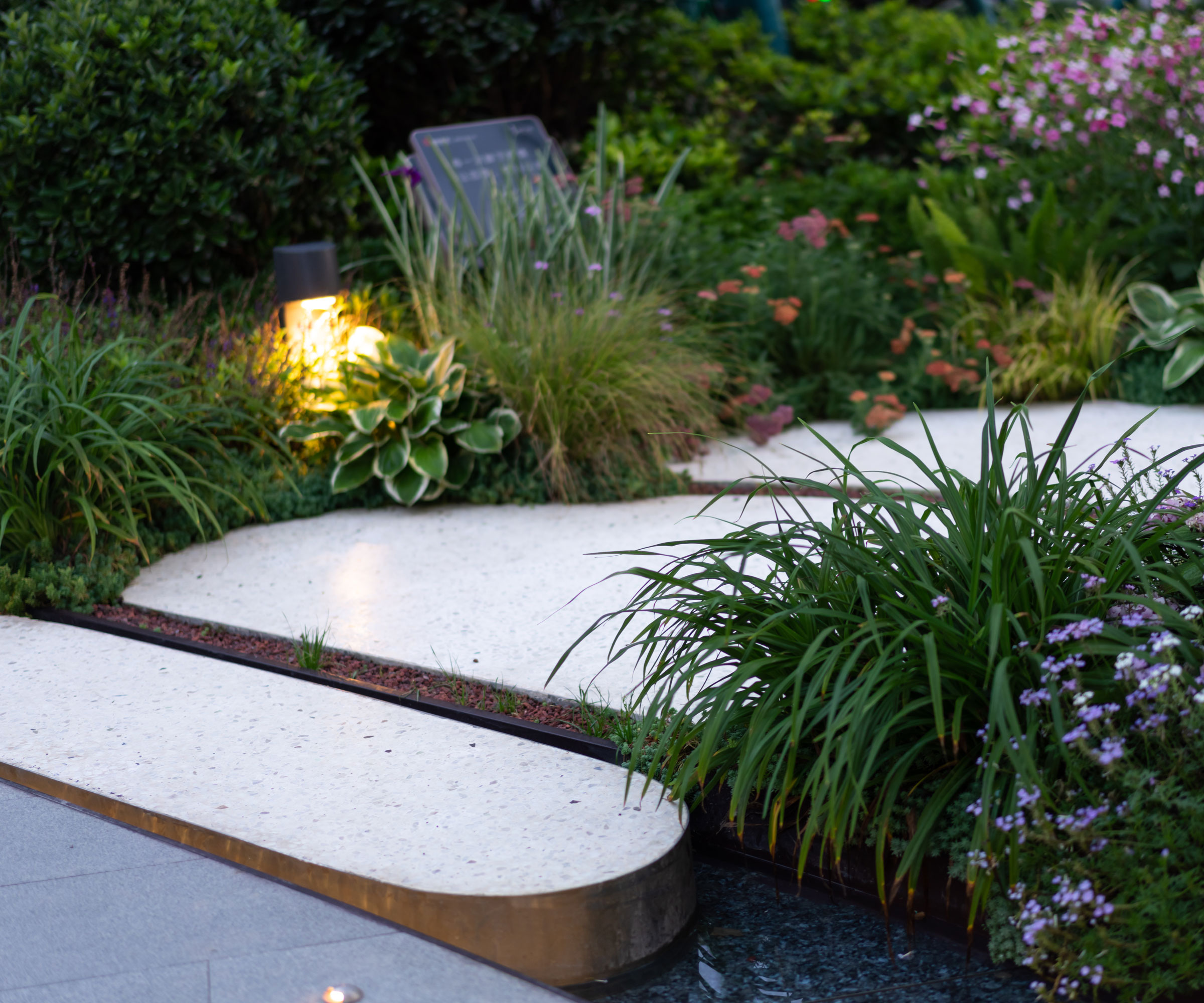 garden path with light, flowers and ornamental grasses
