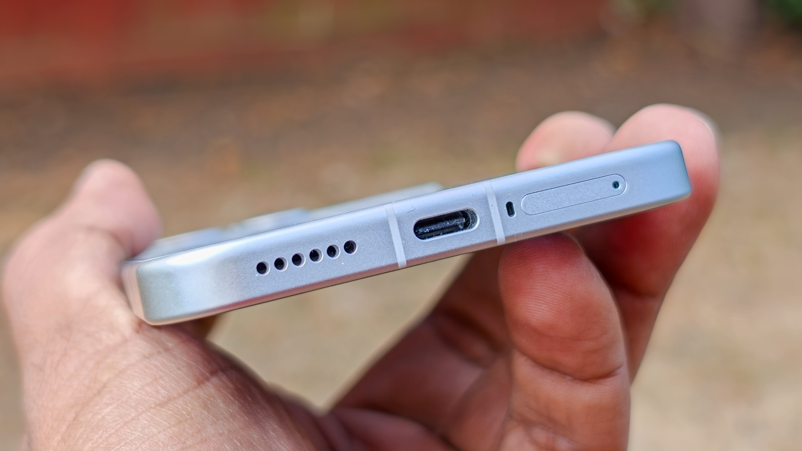 The Poco F8 Pro in Silver in the hand against a garden backdrop