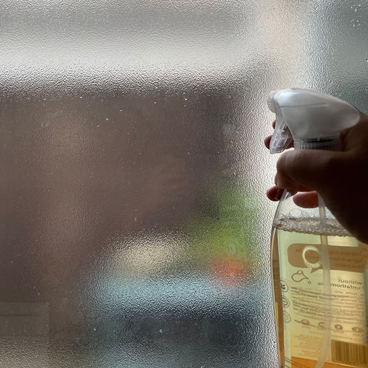 Cleaning the glass of a back door with a bottle of cleaner