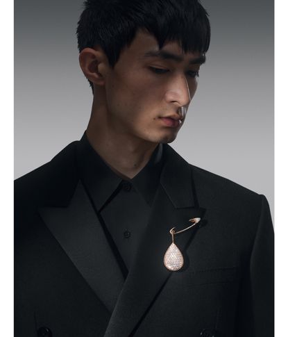 Man in black suit wearing a diamond brooch