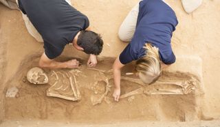 Two researchers excavate a Philistine cemetery at Ashkelon.