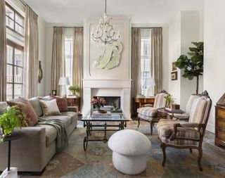 Living room with sofa facing armchairs across coffee table and fireplace in neutral decor