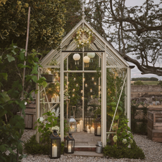 White greenhouse in garden decorating with lanterns and festoon lights.