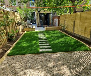A landscape shot of a new garden makeover looking back towards a house with a gravel area, turf with stepping stone path and garden beds either side