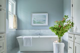 blue bathroom with white bath and partial curtain