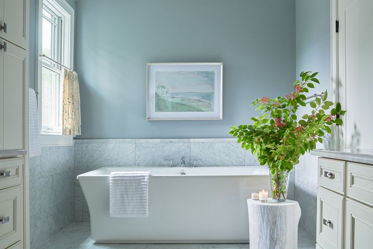 Blue bathroom with white bath and partial curtain