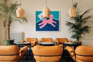Entrance seating with palm trees in pots, copper hanging lights and art on the wall at Prinsengracht venue
