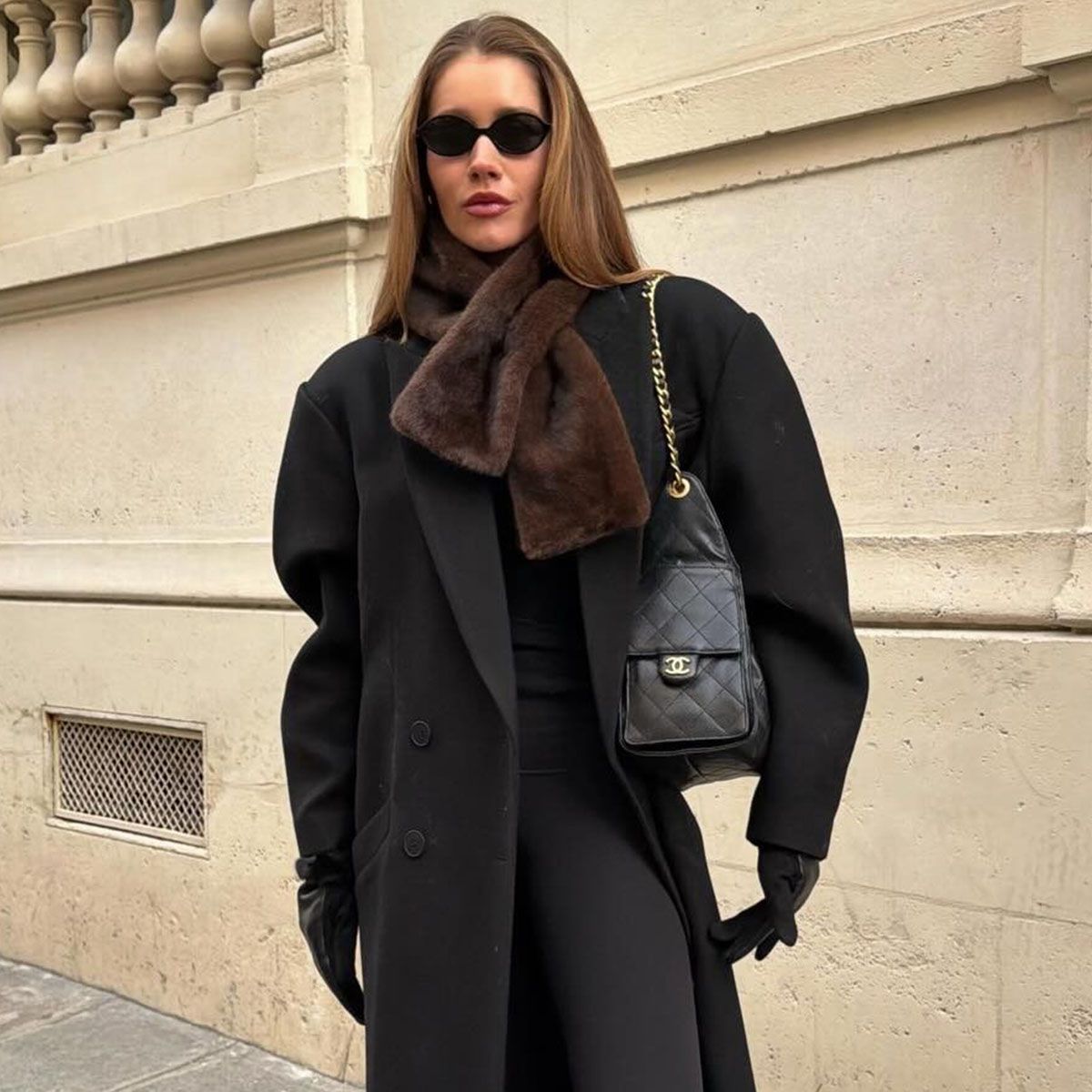 Woman in a black overcoat and brown faux-fur scarf