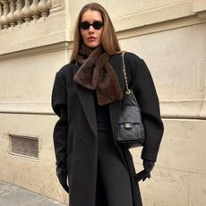 Woman in a black overcoat and brown faux-fur scarf