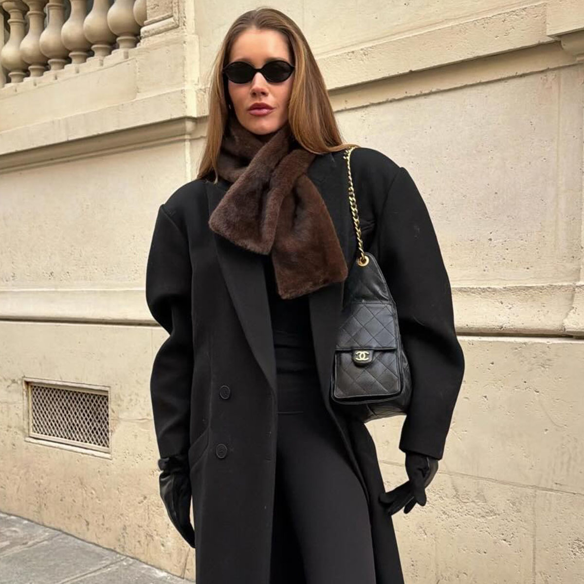 Woman in a black overcoat and brown faux-fur scarf