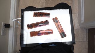 35mm film negatives on a Huion L4S light pad on a person's lap