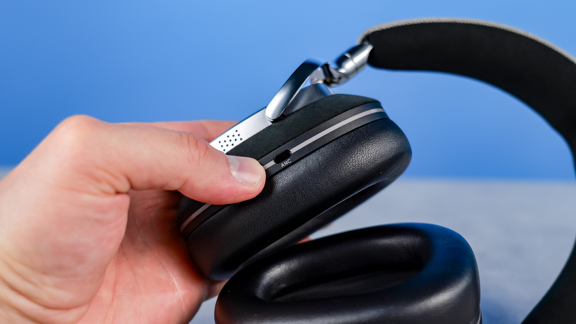 The Noble Audio FoKus Artemis in hand showing the ANC button