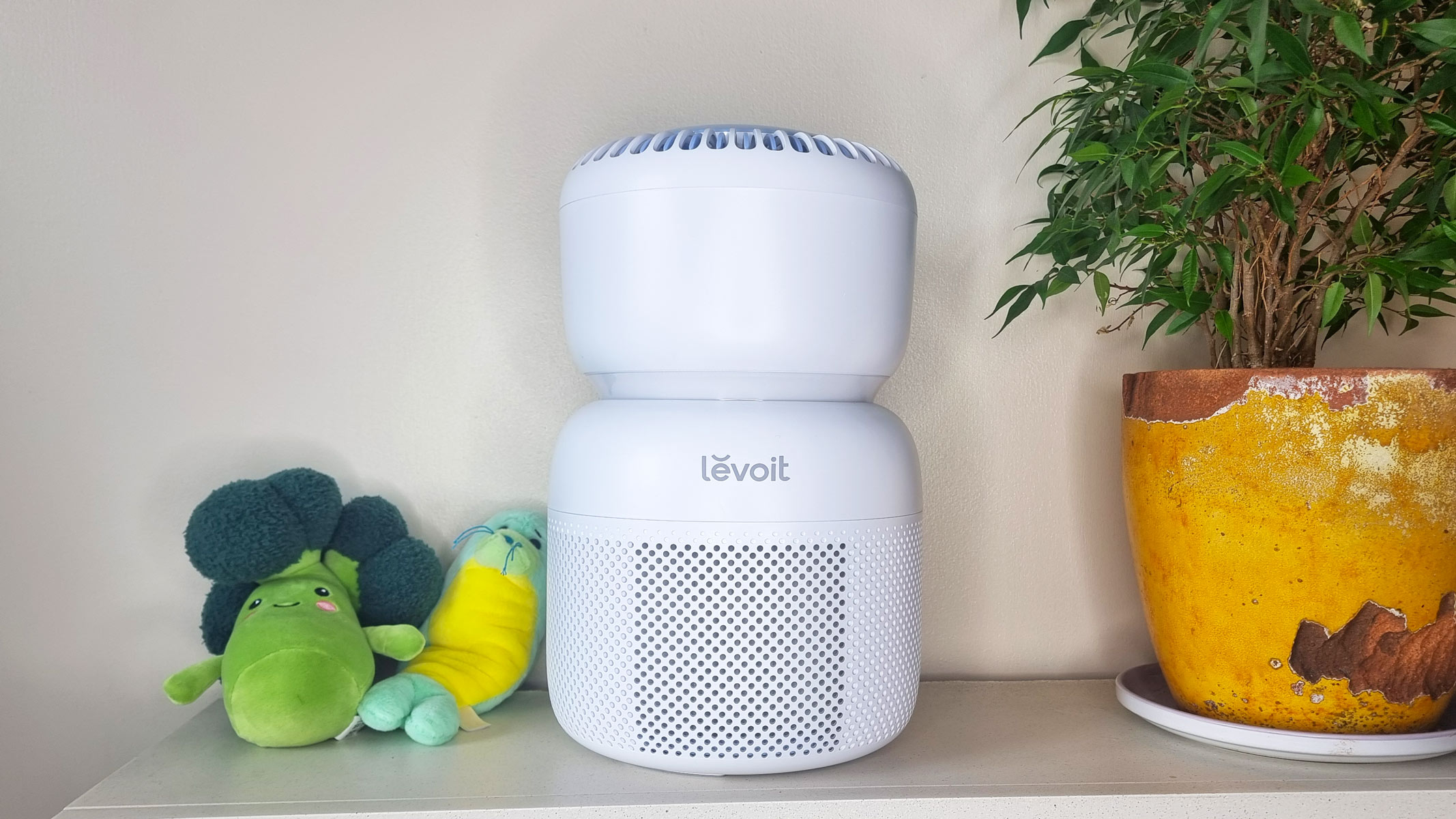 Levoit Sprout air purifier sat next two plushie toys and a houseplant