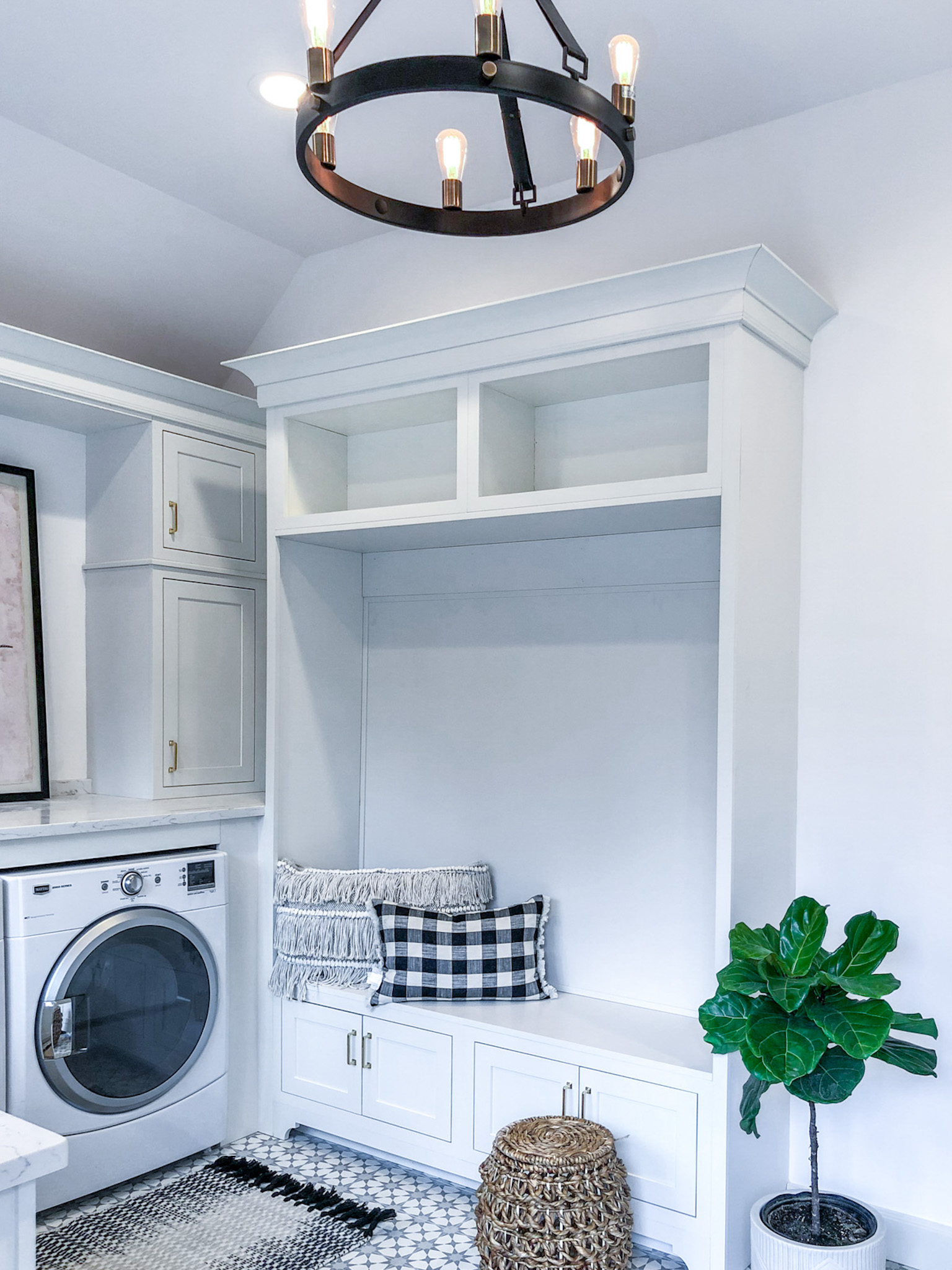 mudroom with washing machine, built in storage and seat, white walls and patterned tile floor