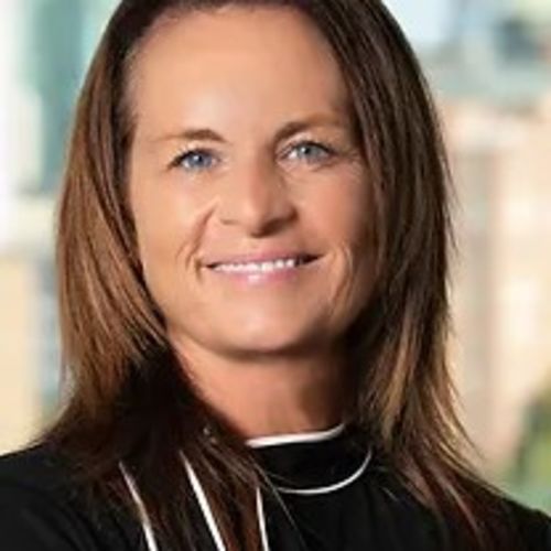 Christine is a tanned woman with light brown hair and blue eyes, pictured wearing a black blouse