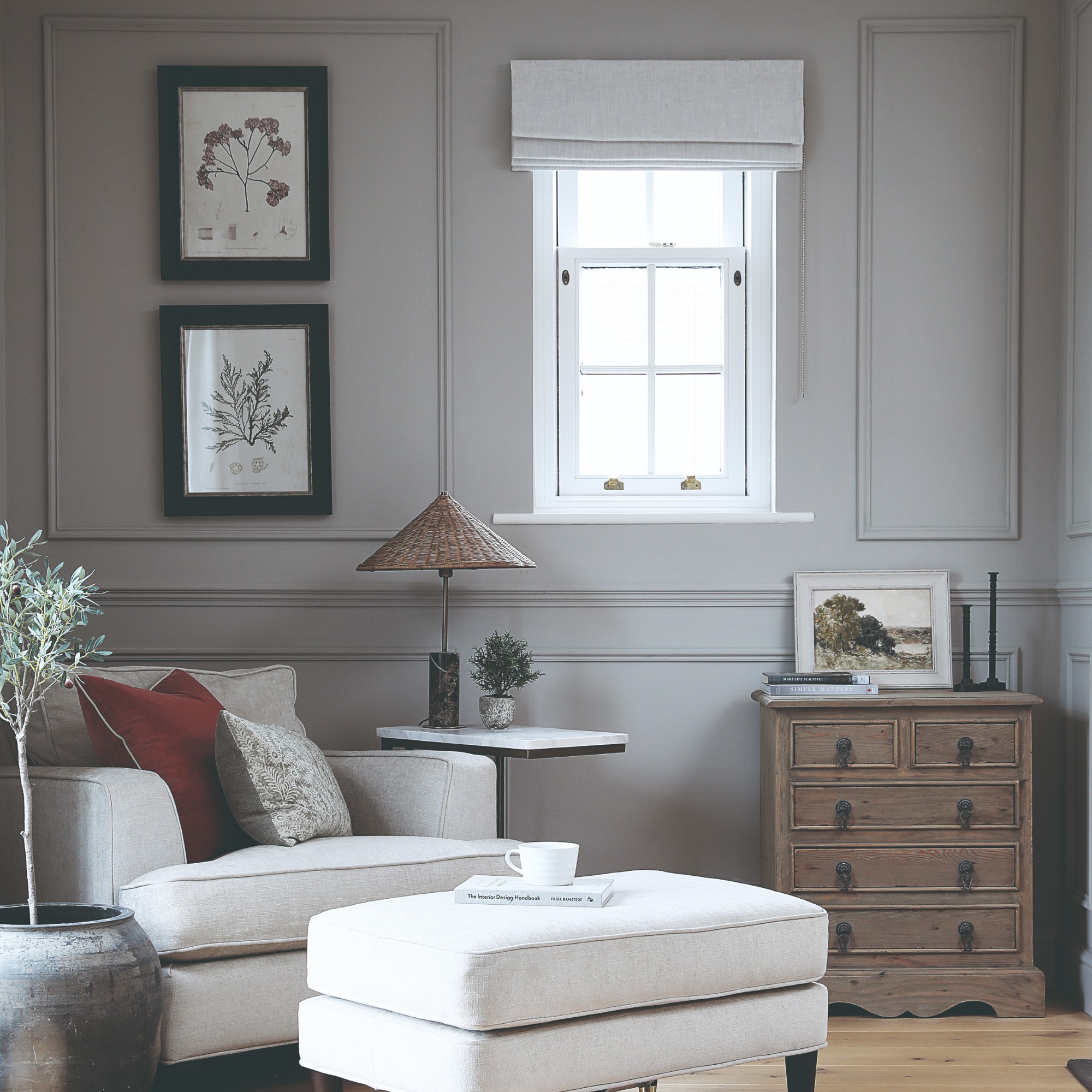 A grey living room with panelled walls and an ivory armchair with a matching footstool