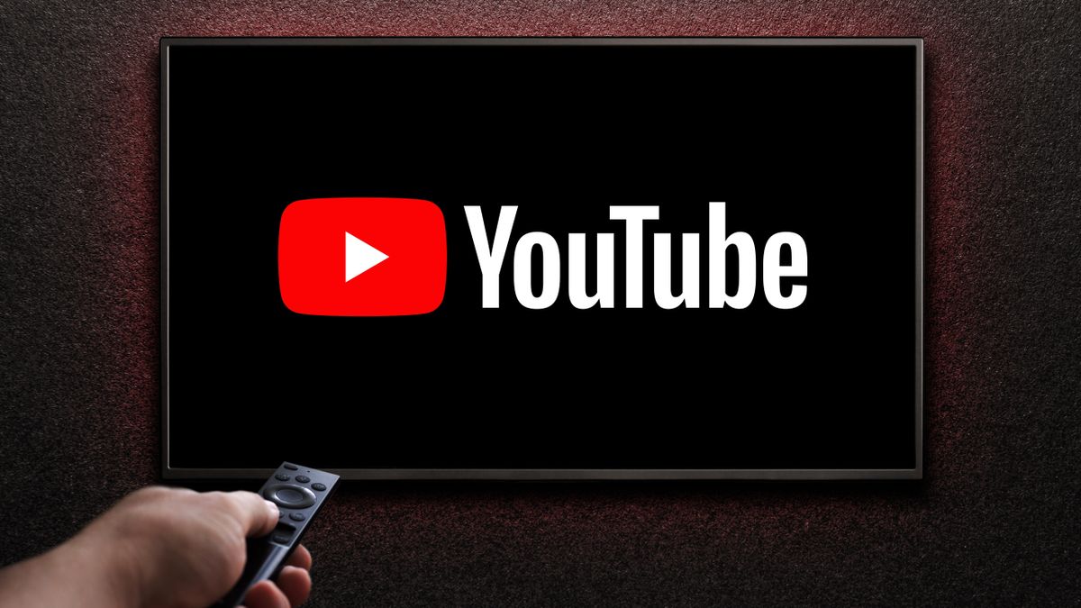 A hand holding a remote pointing at a TV showing the YouTube logo