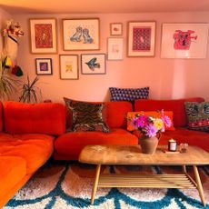 Pink living room with orange sofa and colourful flowers on coffee table