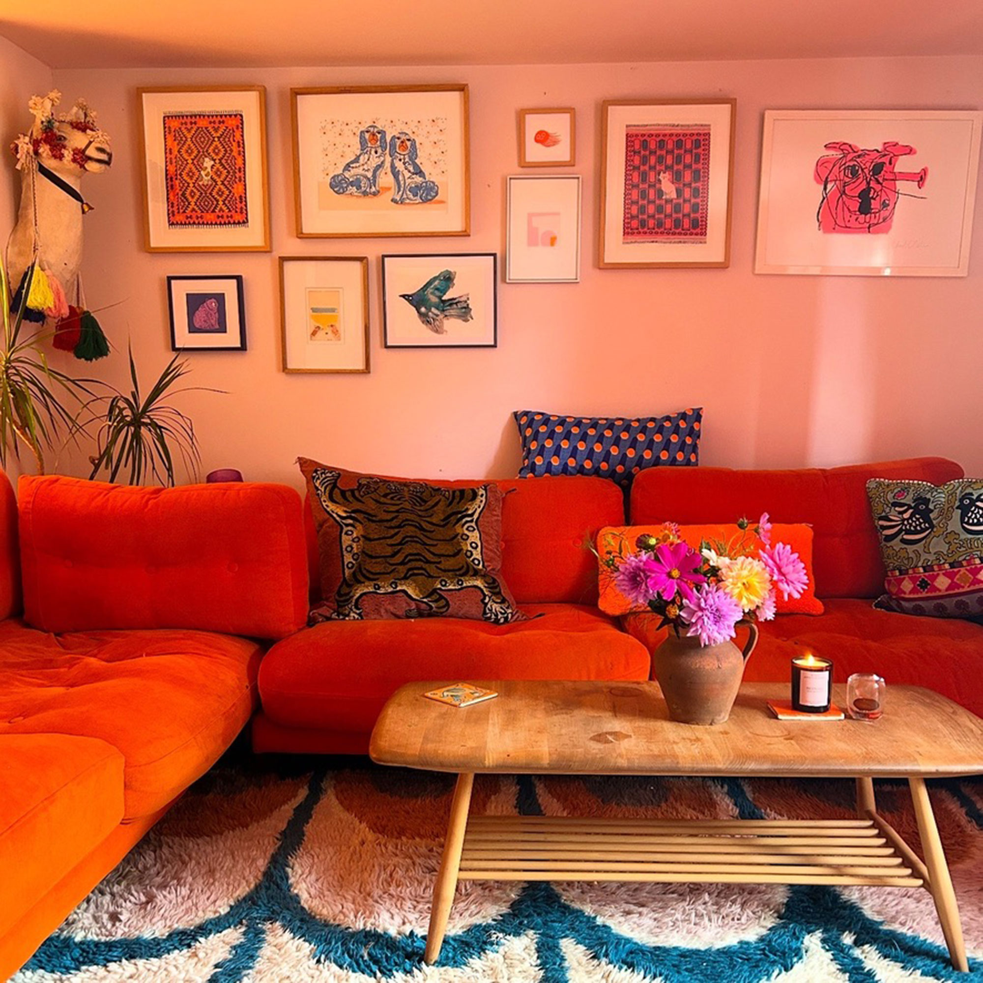 Pink living room with orange sofa and colourful flowers on coffee table