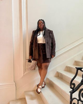 @abimarvel wears a brown skirt suit with two-tone loafers