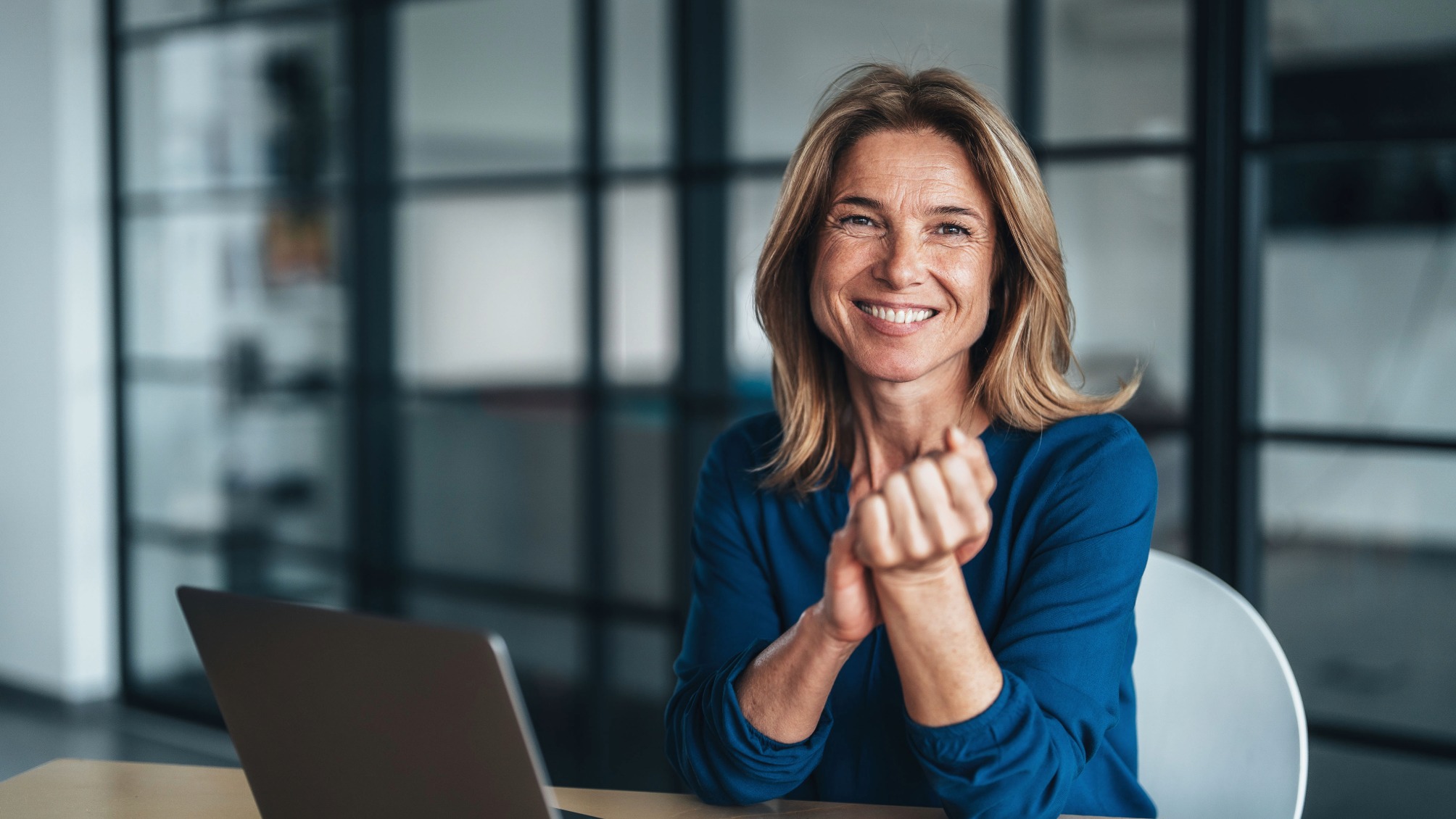 Friendly professional mature woman sitting at a desk in a modern office