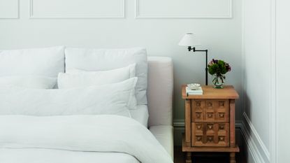 A bedroom with wall panelling and a white-dressed bed