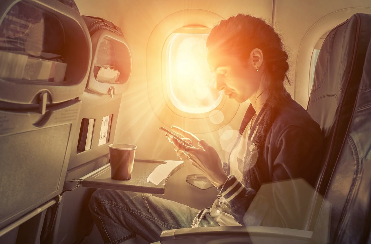 Woman sitting at airplane and looking to mobil phone.