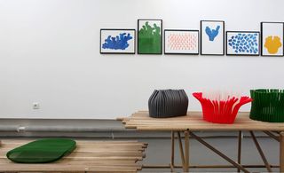 Art display on wooden tables, against a white wall with wall art hanging