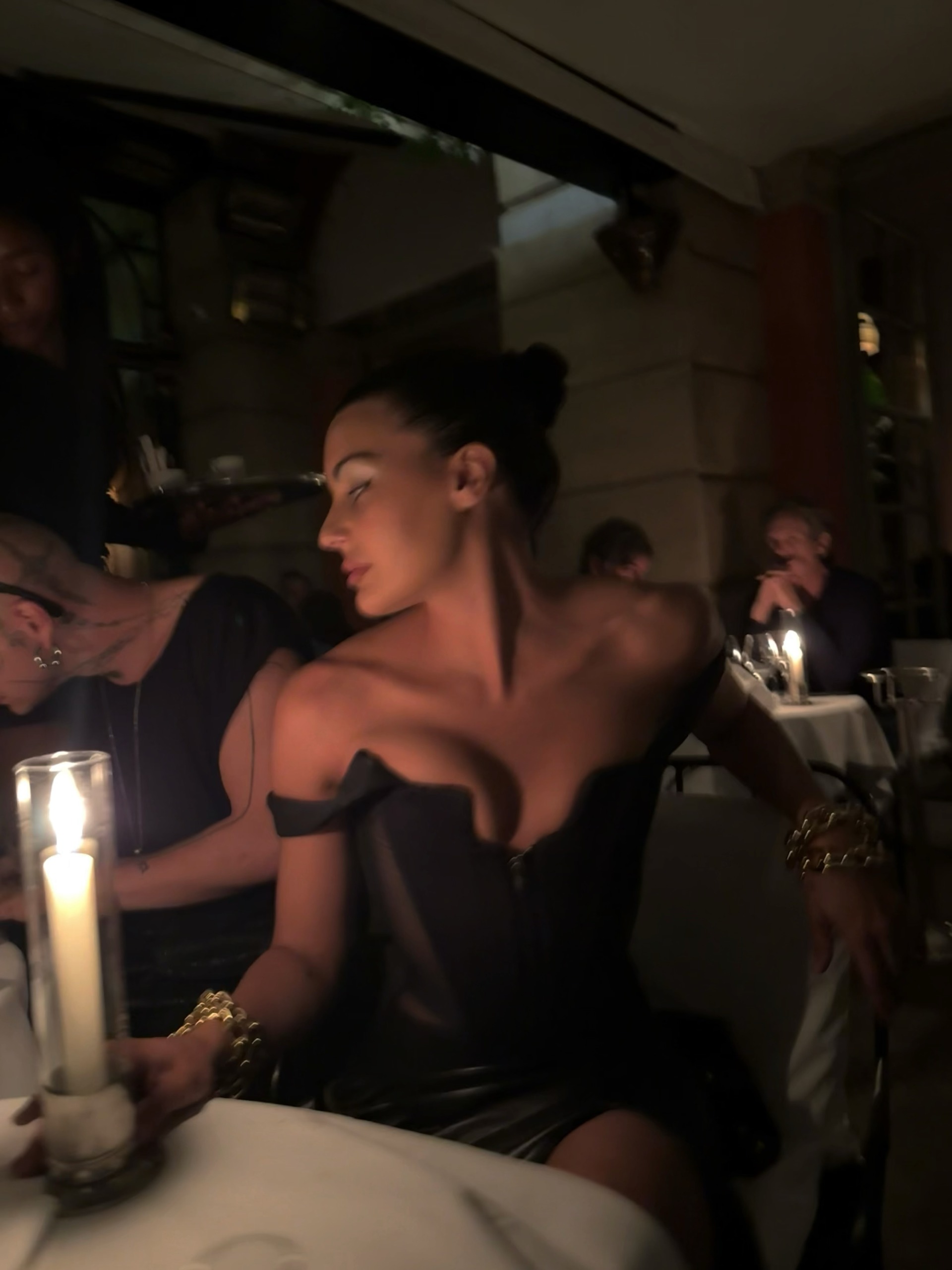 A woman in black illuminated by candlelight.