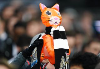 A Newcastle United fan in the crowd holds up an inflatable cat