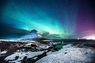 冰岛 Kirkjufell 山的北极光，一名男子路过