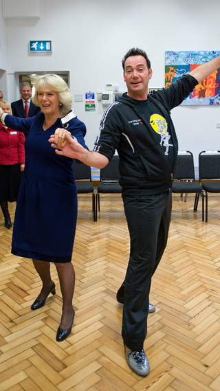 President of the National Osteoporosis Society Camilla, Duchess of Cornwall and Craig Revel Horwood dance the Cha-Cha-Cha during a visit to St Clement Danes School on October 20, 2009 in London, England