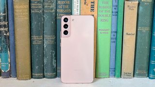 galaxy s22 plus in pink leaning against antique books