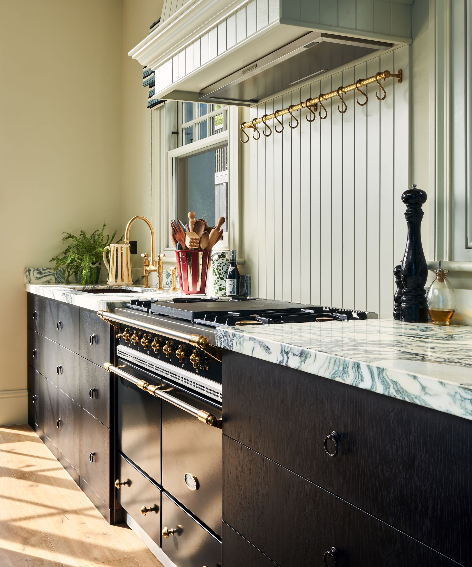 A kitchen with muted green walls, dark brown cabinets and muted blue paneled backsplash