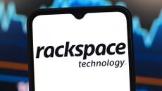 Rackspace logo and branding pictured on a smartphone screen with stock market graph pictured in background.