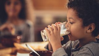 A little boy drinks a glass of milk.