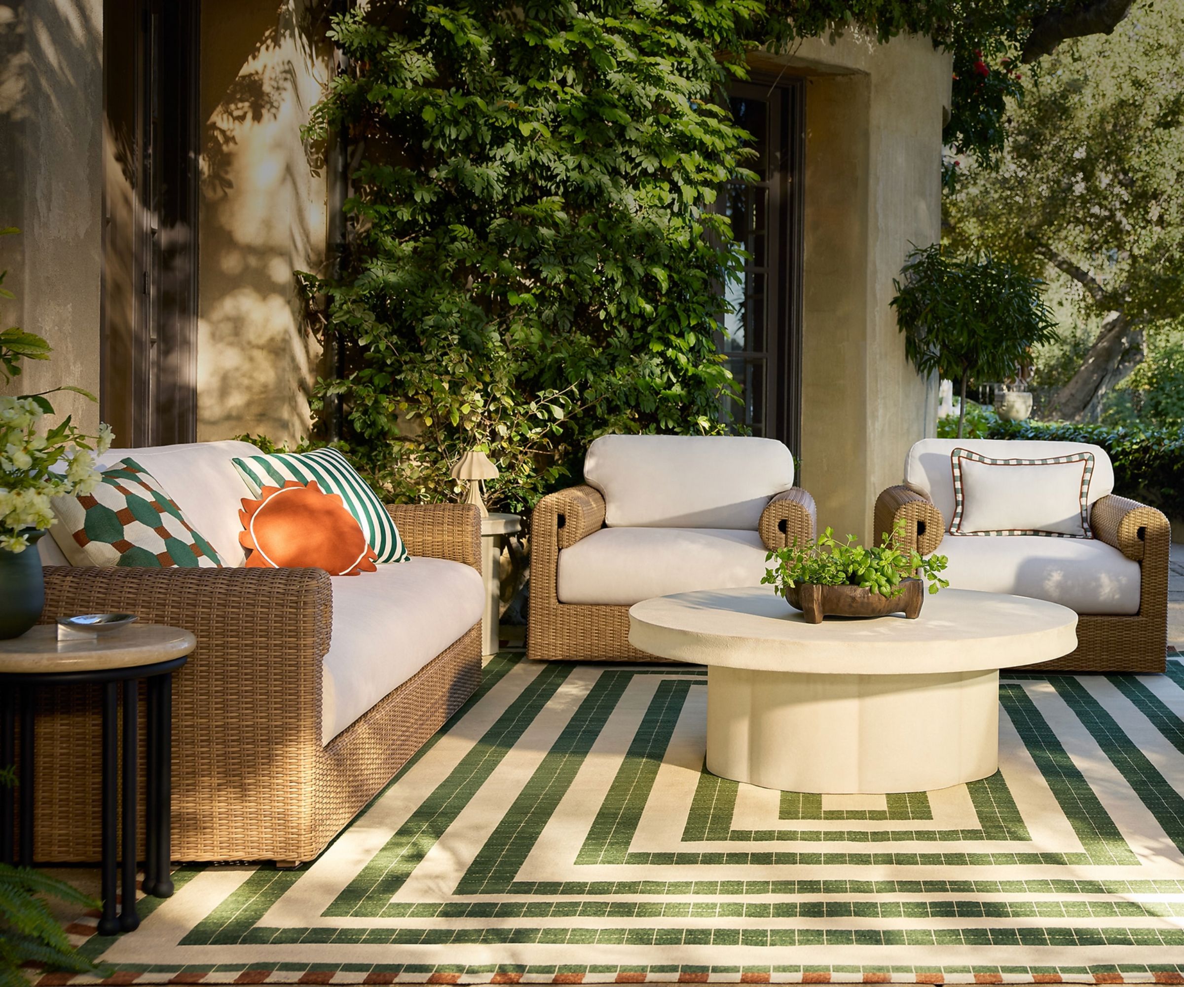 Outdoor living area with tile-effect green and white rug and rattan seating