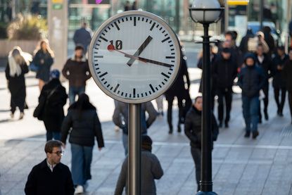UK productivity: people waling past a clock in Canary Wharf
