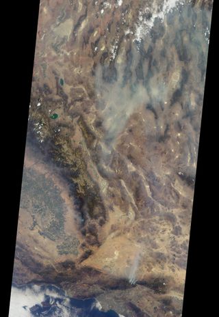 Natural-color satellite image of the Blue Cut wildfire in Southern California midday on Aug. 17, 2016. Los Angeles is pictured by the coast, with three smoke plumes rising in the north.