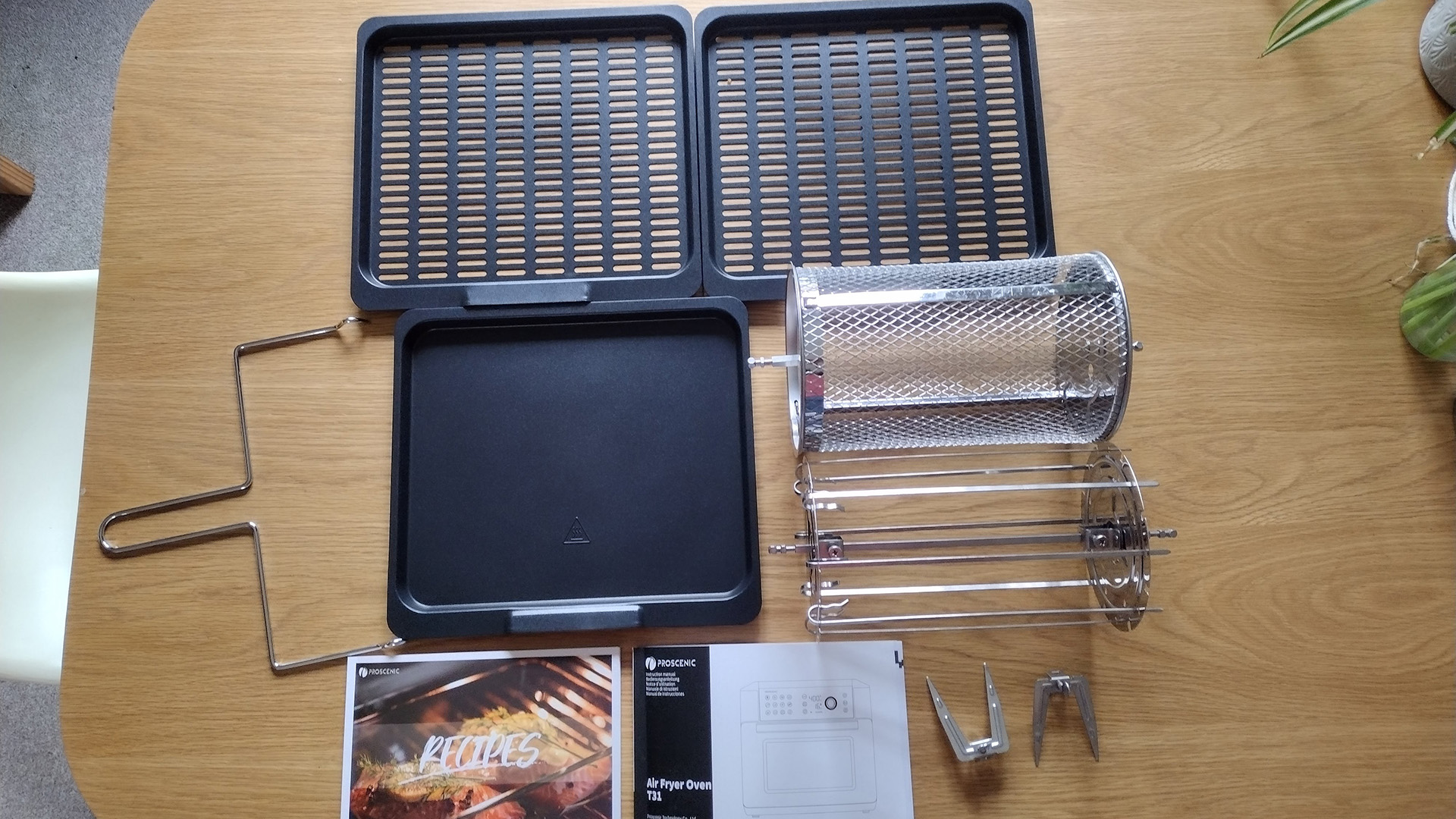 Proscenic air fryer parts laid out on a table.