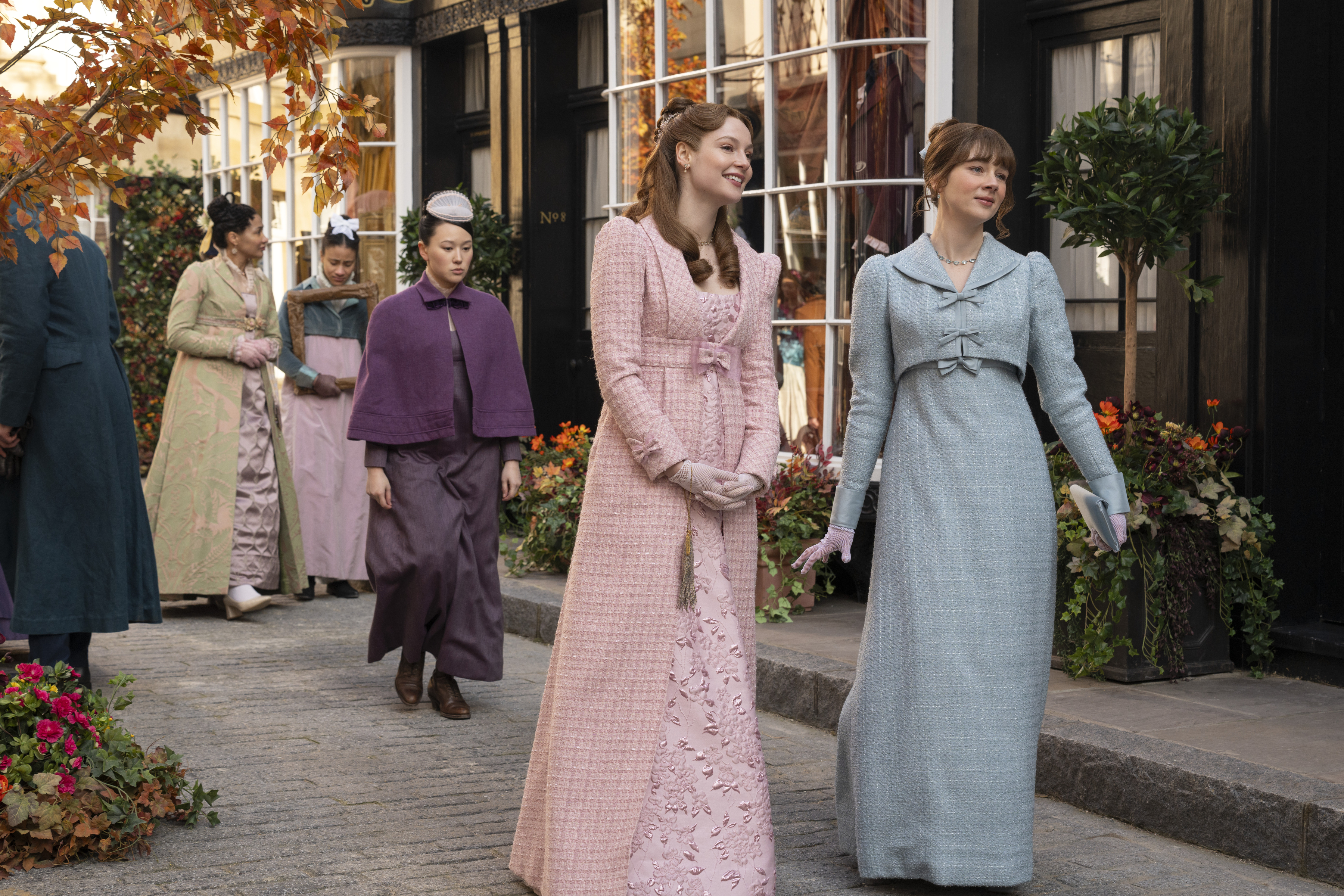 A woman dressed as a maid (Yerin Ha as Sophie Baek) walks behind two women (Hannah Dodd as Francesca Bridgerton and Claudia Jessie as Eloise Bridgerton) as they stand in a busy Regency-era street, in episode 405 of 'Bridgerton.'