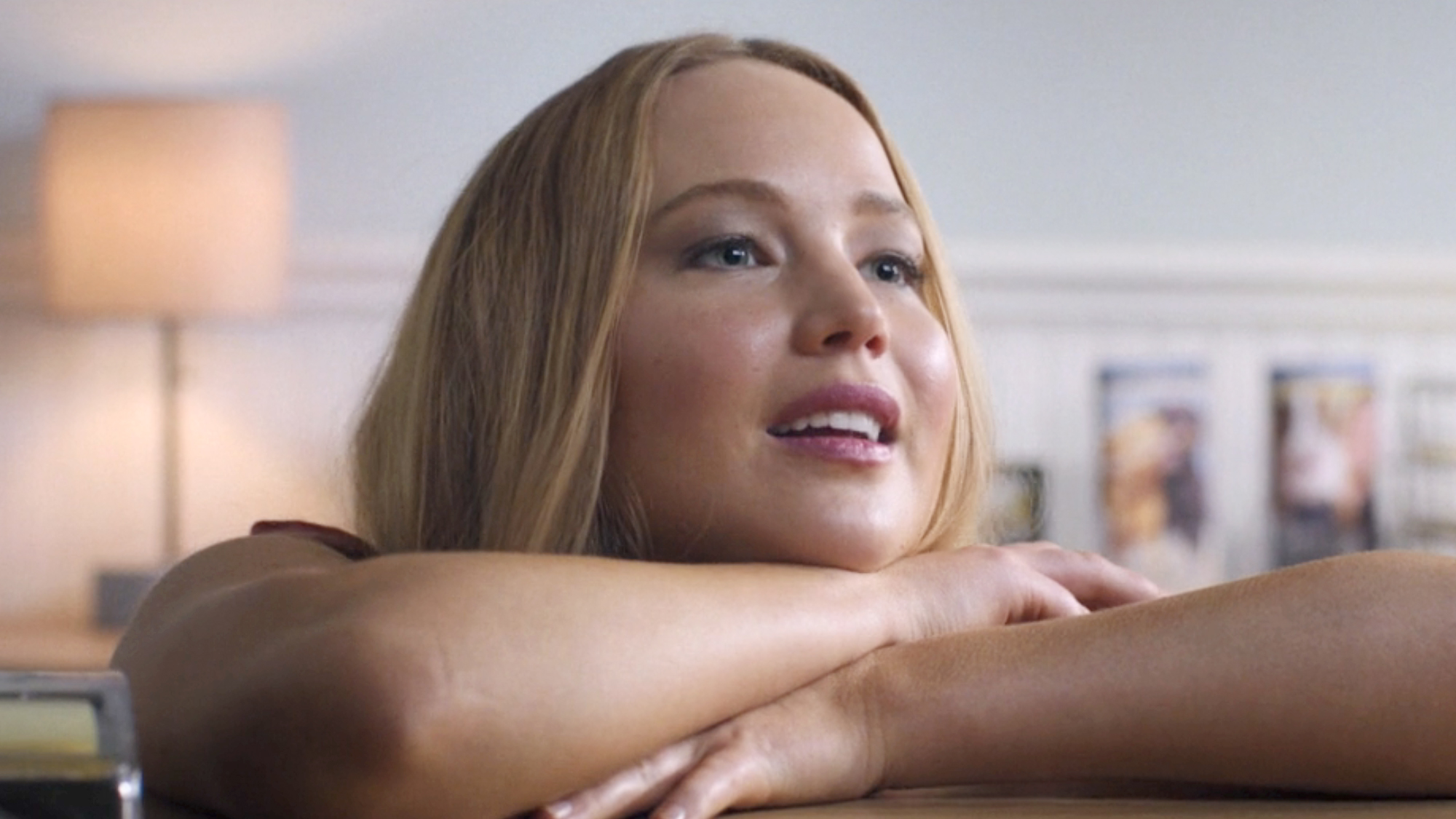 Jennifer Lawrence wearing a red dress and leaning on a desk in No Hard Feelings (2023).