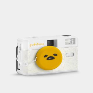 The Gudetama cameras from a different full frontal angle. It has a white leatherette camera and an egg shaped lens cap