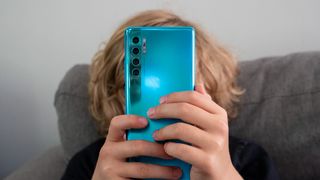 A picture of a boy holding a blue TCL 20 Pro phone