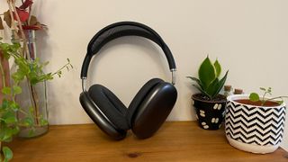 Space grey Apple AirPods Max on a wooden desk next to plants