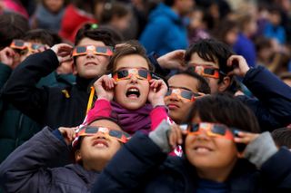 Children use special glasses to look at the sky during a partial solar eclipse outside the Madrid Planetarium on March 20, 2015. The United States is one day away from an epic total solar eclipse on Aug. 21, 2017.