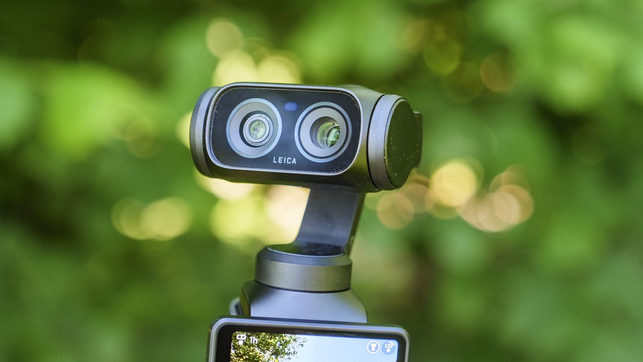 Closeup of the Insta360 Luna Ultra vlogging camera's dual lenses, leafy background