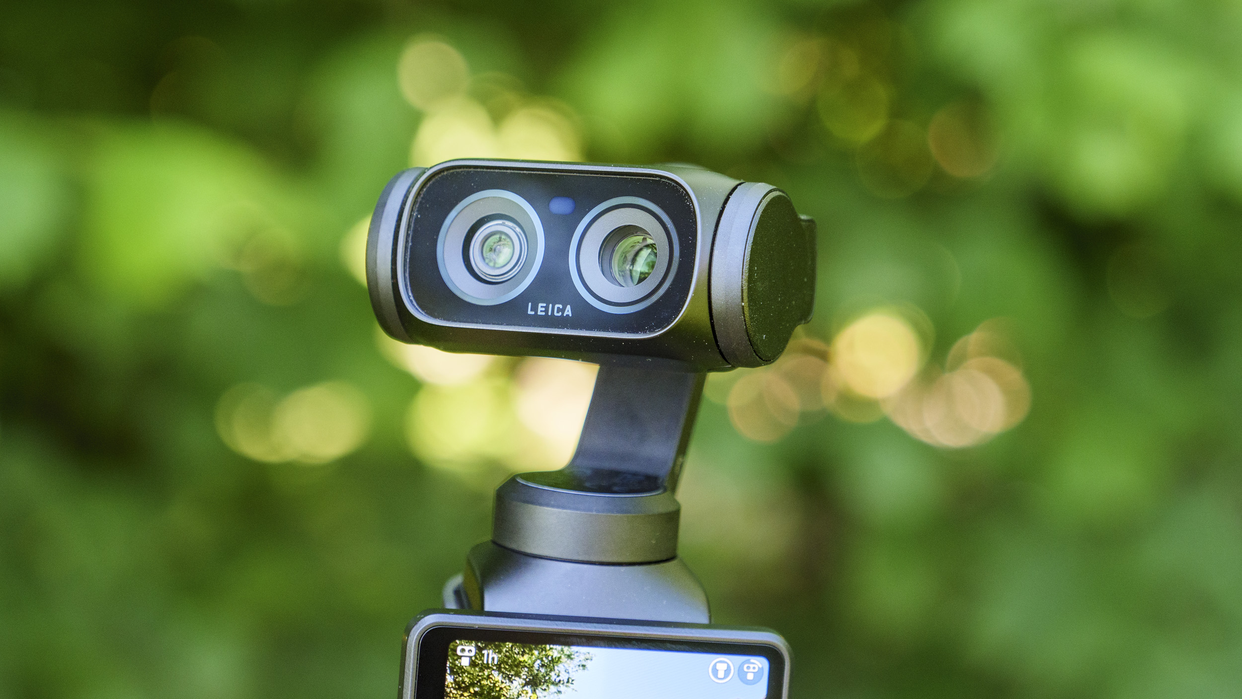 Closeup of the Insta360 Luna Ultra vlogging camera's dual lenses, leafy background