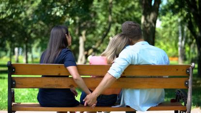 A man sat on a bench with two women