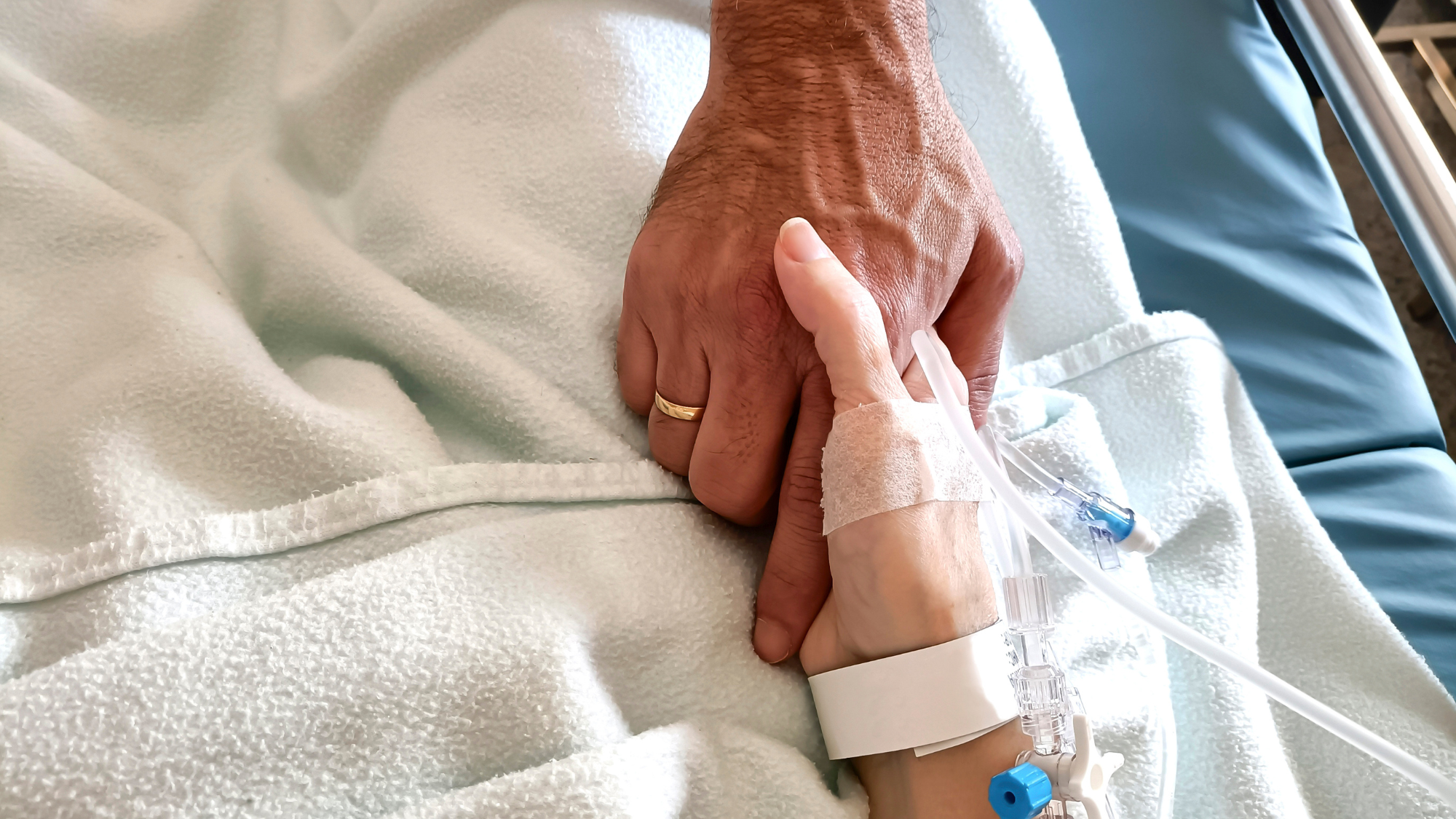 Close up on man and woman holding hands in hospital